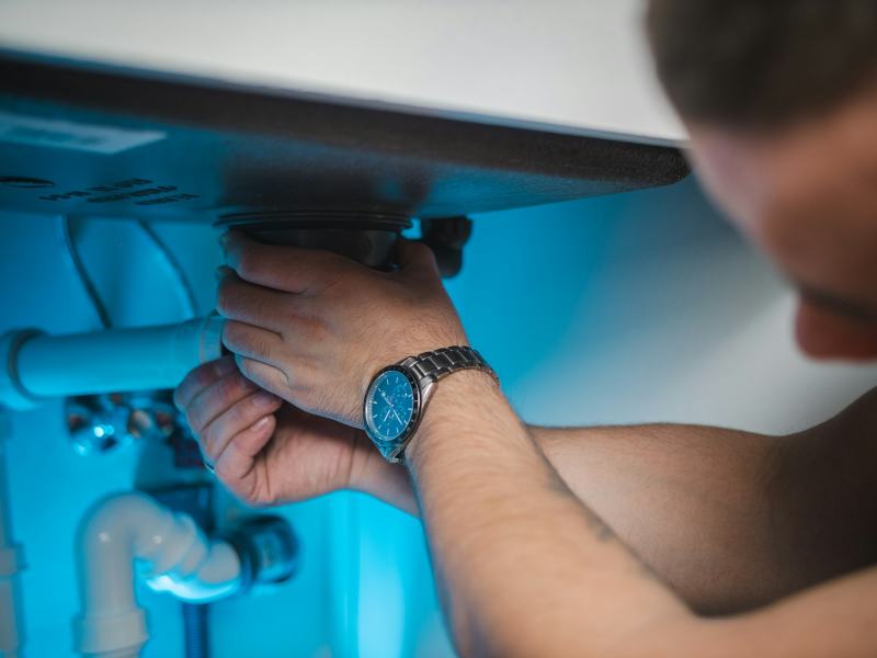 A plumber holding a screw-in heating element pulled from an electric tank to replace a water heater heating element
