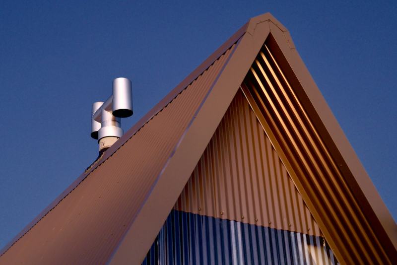 A roofer fitting a new rubber collar around a plumbing vent pipe to replace a roof vent boot