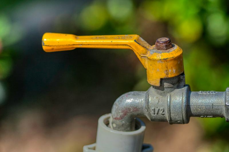 A plumber fitting a new brass ball valve to replace a main water shut-off valve at the house entry