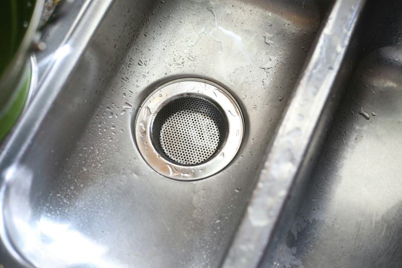 A plumber mounting a new unit under the sink to replace a garbage disposal