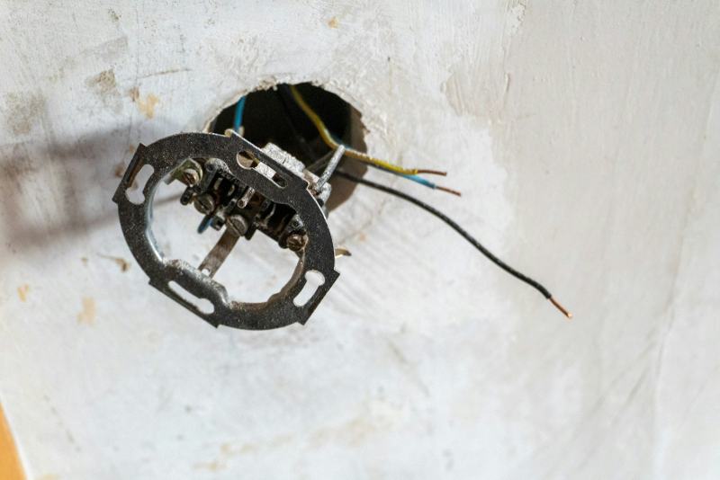 An electrician fishing new cable through a wall to move an electrical outlet to a new location
