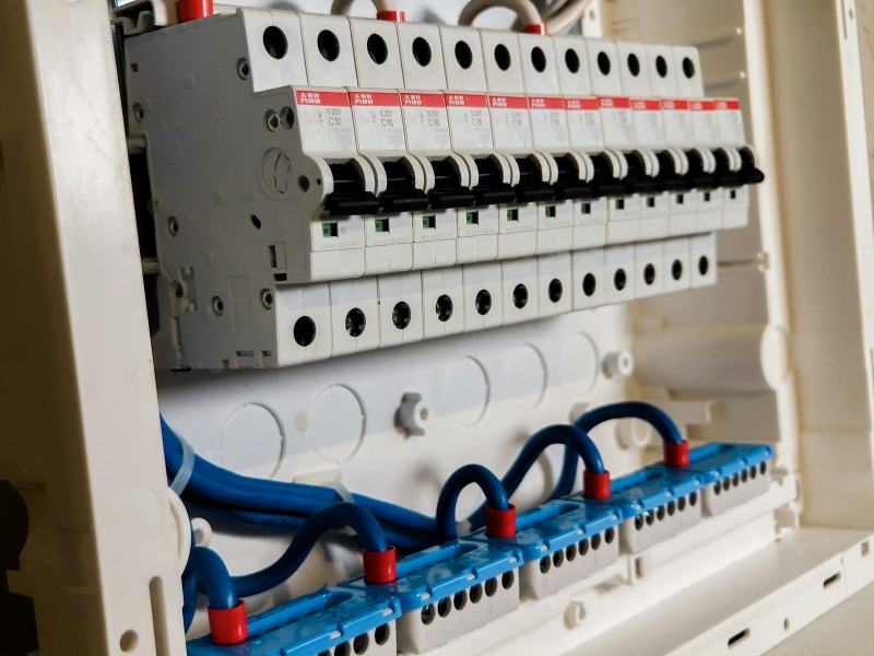 An electrician about to install a whole-house surge protector next to the main breaker panel