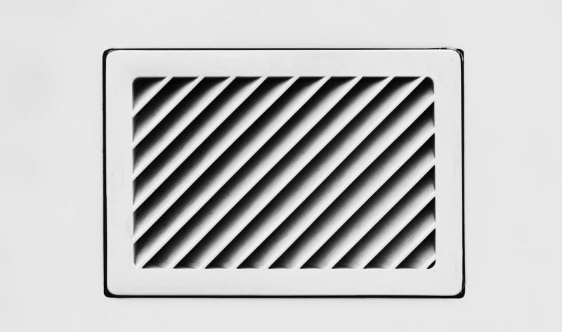 An HVAC technician installing a new return air grille on a bedroom wall to add a return air duct