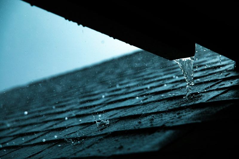 A roofer fitting a metal strip along the eave to add drip edge to a roof before the shingles