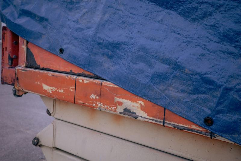 Roofers securing a heavy blue tarp over storm damage as an emergency roof tarp