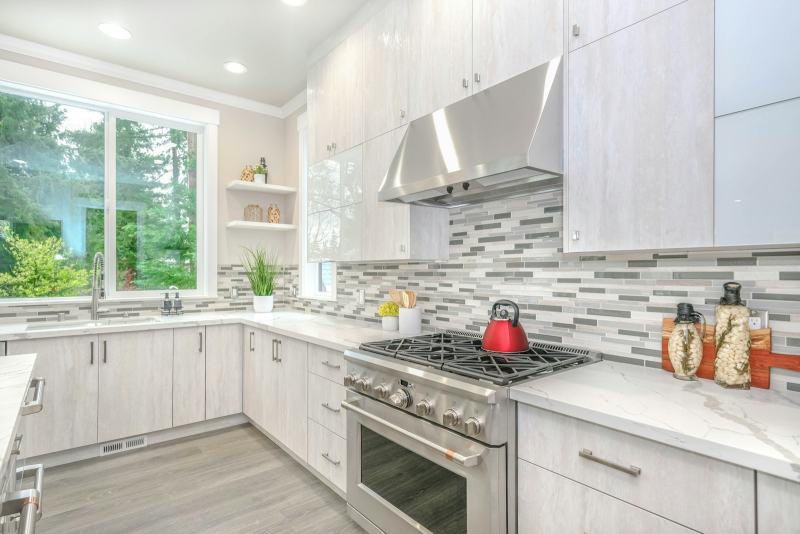 A tile setter pressing subway tile onto the wall to install a kitchen backsplash behind the counter
