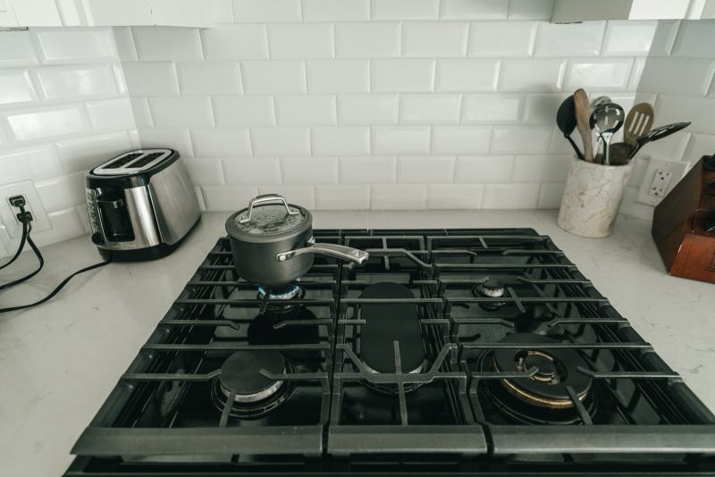 A plumber mounting a folding arm faucet on the wall to install a pot filler above the range
